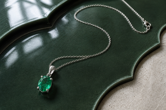 Lab-grown emerald pendant necklace on green ceramic with fine silver chain