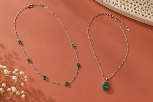 Green gemstone station necklace and pendant arranged on a coral surface.