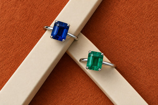 Blue and green emerald-cut gemstone rings on intersecting display bridges, editorial illustration