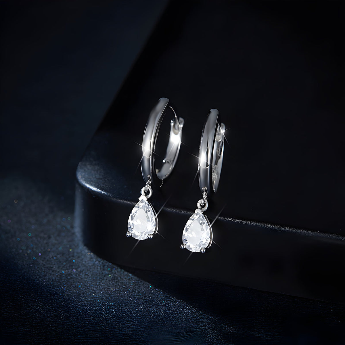 Pear-cut moissanite drop earrings displayed on black
