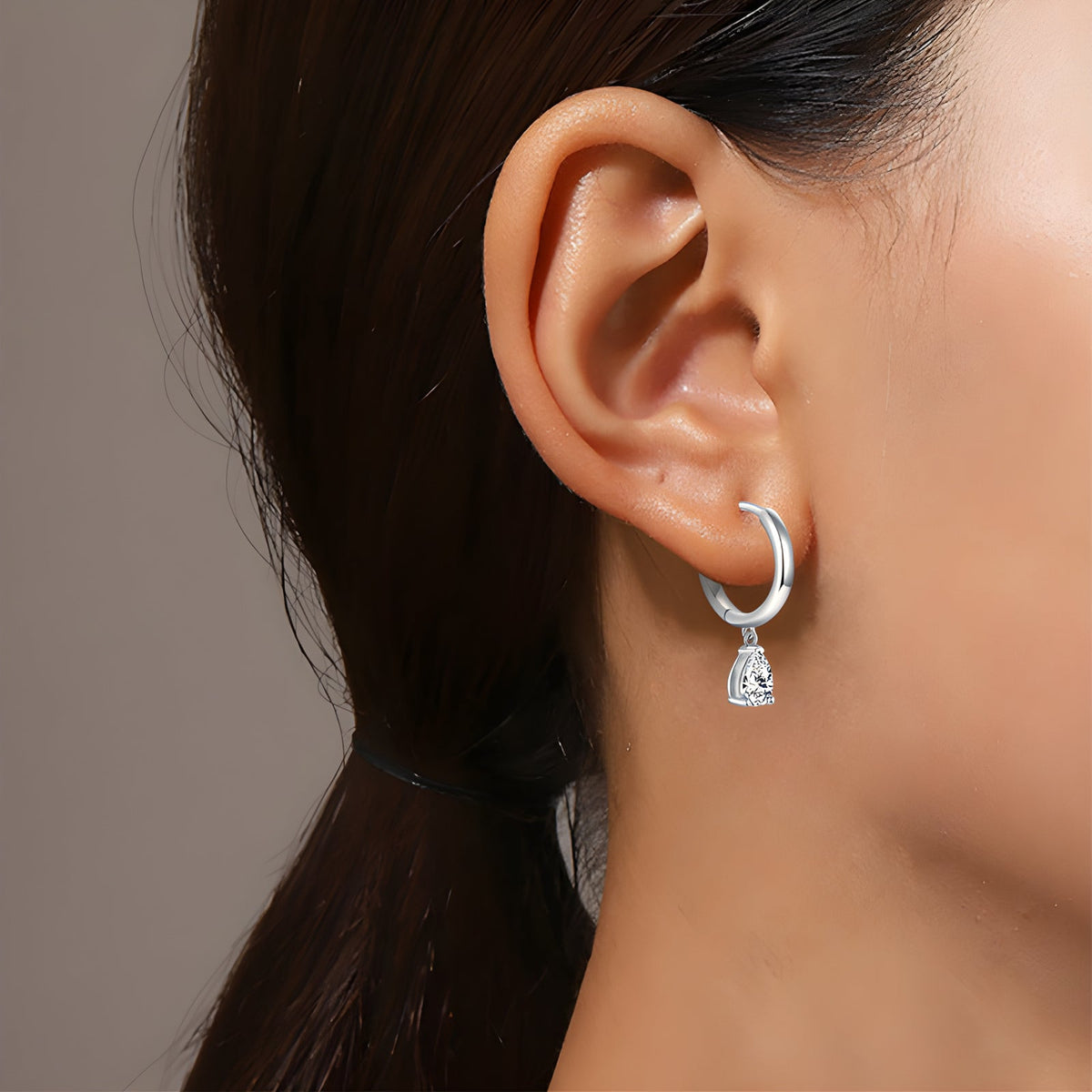 Silver pear-cut moissanite drop earring worn on the ear