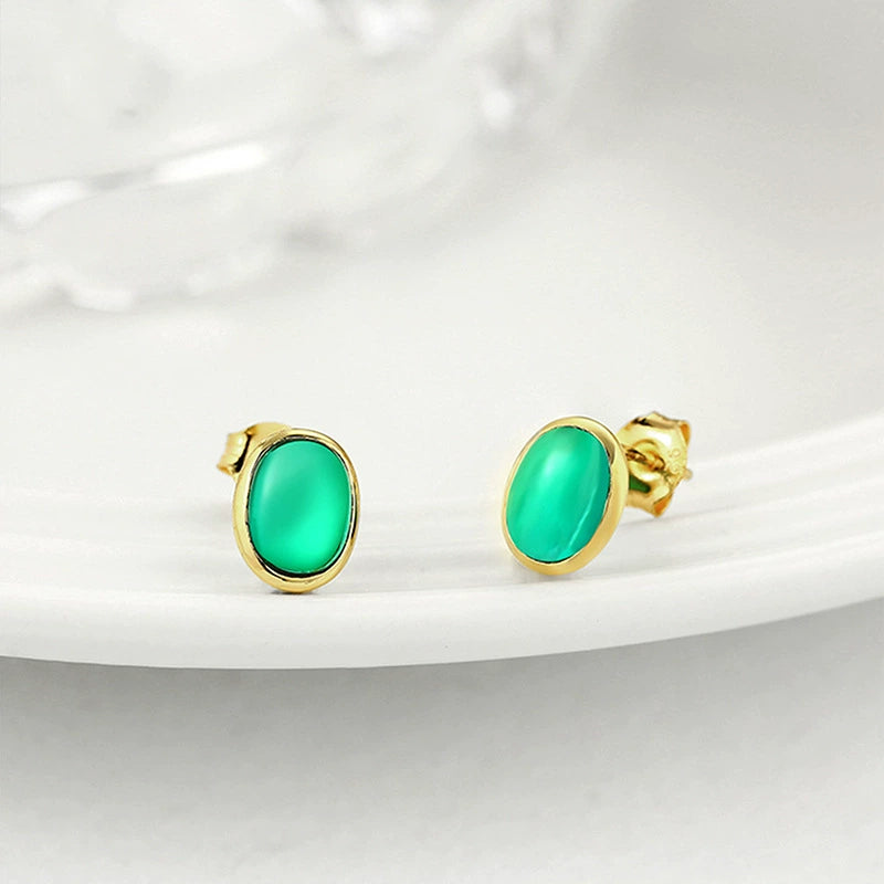 Angled view of a pair of green lab-grown emerald bezel stud earrings